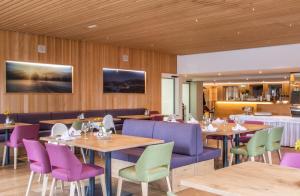 林格瑙阿德尔酒店的餐厅设有紫色和绿色的椅子和桌子