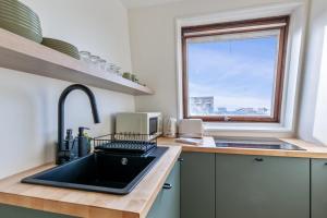 多维尔Brand new studio with sea view in the Deauville port - Welkeys的厨房设有黑色水槽和窗户。