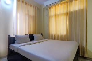巴特那FabExpress Buddha Residency的一间卧室配有一张带白色床单的床和一扇窗户。
