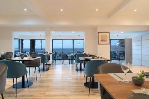 伊基克NH Iquique Costa的餐厅设有桌椅,以大海为背景