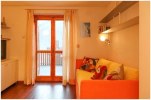 格雷索圣尚[Casa Quadrifoglio] a 3 minuti dalle piste da sci的客厅配有橙色沙发和滑动玻璃门