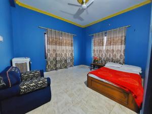 拉明德Tathāgata Homestay的卧室拥有蓝色的墙壁,配有一张床和一张沙发