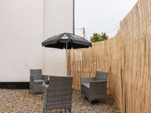 托波因特Carew Lodge & Loft的庭院设有三把椅子和一把伞,旁边是栅栏