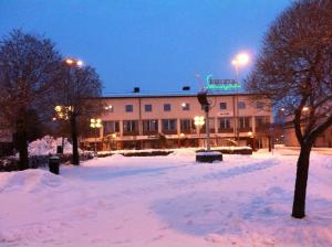 马隆Hotell Skinnargården的一座晚上下雪的建筑