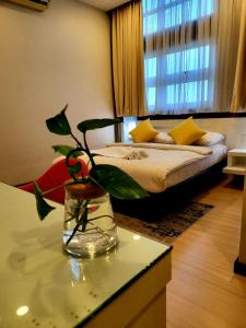 关丹Lovita Hotel Kuantan的一间有床的房间和一个带植物的玻璃花瓶