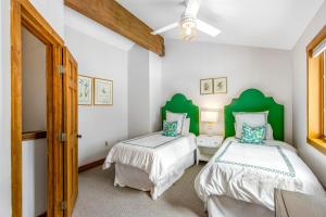 埃文2 Bed 2 Bath Apartment in Avon的配有绿色床头板的客房内的两张床