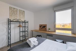 雷恩Le Cocon Voltaire - Appartement 2 chambres avec parking - Mabilais的一间卧室配有一张床、一张书桌和一个窗户。