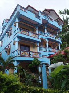 长滩岛Ocean Breeze Inn的带阳台和树木的蓝色建筑