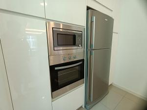 马六甲Pax 6+3 Grand Lux Melaka homestay的厨房配有不锈钢冰箱和微波炉。