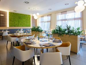 加尔达湖滨加尔达运动俱乐部酒店的一间设有桌椅的餐厅,种植了植物