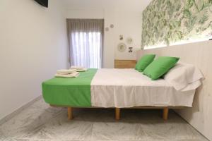洛斯马蒂雷斯203 I Posada del Mar I Encantador hostel en la playa de Gandia的一间卧室配有一张带绿色枕头的床。