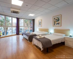 瓦伦西亚Suites Rooms Valencia的客房内设有两张床,铺有木地板,设有窗户。