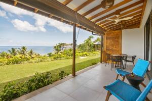 塔卡马卡Paradise Chalets Yoga & Wellness的一个带桌椅的户外庭院和大海