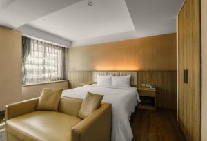 台中市美之旅商务饭店的酒店客房,配有床和沙发