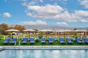 加德纳Wildflower Farms, Auberge Resorts Collection的一组椅子和遮阳伞,位于游泳池旁