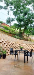 德班Orange Leaf Guesthouse Durban North的砖墙前的一张野餐桌和两把椅子