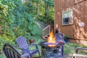 加特林堡Cozy Cabin with Mountain Views Near SkyLift Park!的庭院设有两把椅子和一张带火坑的桌子