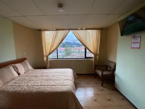 昆卡Hostal el Paraíso的一间卧室设有一张床、一个窗口和一把椅子