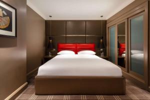 伦敦Radisson Blu Sussex Hotel, London的一间卧室配有一张大床和红色床头板
