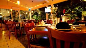 图拉德阿连德Hotel Real Home的一间设有木桌、椅子、盘子和玻璃杯的餐厅