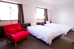 大分大分宫古町绿富酒店的酒店客房,设有两张床和一张红色椅子