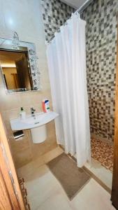 马拉喀什Luxury apartment Gueliz (2 min walk from Train Station)的浴室设有白色的淋浴帘和水槽