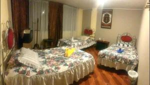 科塔卡奇Hostal Jora Continental的一间设有两张床的房间和一间带两张桌子的房间