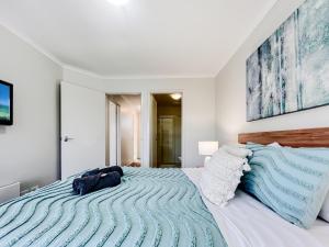 梅林布拉Seachange Apartments Merimbula的一间卧室配有一张带蓝白色床单的大床