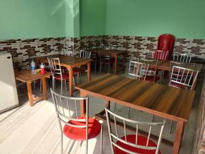 JhirnaCorbett Rejoice Home Stay的餐厅设有木桌和红色椅子