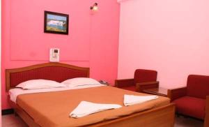 马尔冈马尔冈住宿酒店的粉红色的卧室,配有一张床和一把红色椅子