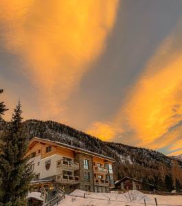 采尔马特全景滑雪公寓式酒店的雪中与日落的建筑物