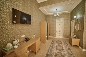 撒马尔罕Comfort Hotel Samarkand的一间墙上配有电视的房间和一间配有书桌的房间