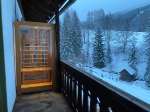 巴德小基希海姆Nockalm Cottage的阳台的门,眺望着雪覆盖的森林