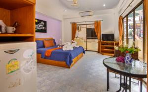 芭堤雅市中心旅行者休息运动酒吧酒店的一间卧室配有一张床铺、一张桌子和一台冰箱