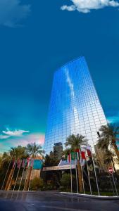科威特AlHamra Hotel Kuwait的一座高大的镜子建筑,前面有棕榈树