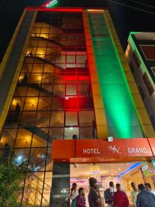 商沙巴Hotel MN Grand Shamshabad Airport Zone Hyderabad的一座有彩色窗户的建筑,前面的人在走