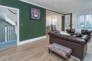 伦敦The London House - Entire Villa的客厅设有棕色真皮沙发和绿色墙壁。