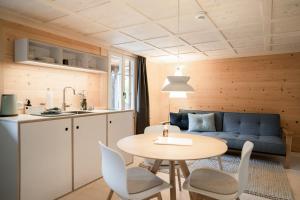 伦克Cortesi's Lenk Lodge, Boutiques Appartements的厨房以及带桌子和蓝色沙发的客厅。