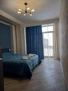 萨克德佐尔镇Alvina complex的一间卧室配有一张带蓝色床单的床和一扇窗户。