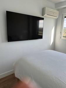 里瓦斯-巴西亚马德里德Apartamento cerca centro Madrid的卧室配有白色的床和平面电视。