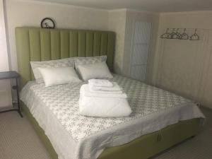 博罗沃耶Современные и уютные аппартаменты的一张带绿色床头板的床铺,上面有毛巾