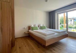 塞博登Seespitz 37 - Ferienwohnungen Eisendle的一间卧室配有一张带绿色枕头的床和一扇窗户