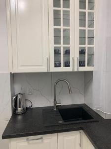 拉塔Jurata Apartament Glamour的厨房柜台配有水槽和白色橱柜