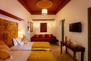 马拉喀什Riad les remparts de la kasbah的酒店客房带两张床和一张红色沙发