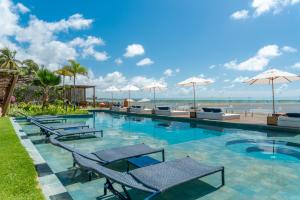 马拉戈日Villa Pantai Boutique Hotel Maragogi的一个带椅子和遮阳伞的游泳池