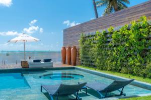 马拉戈日Villa Pantai Boutique Hotel Maragogi的一个带椅子和遮阳伞的游泳池