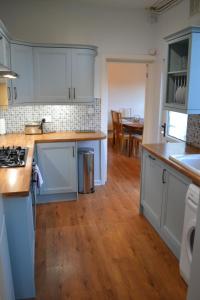 卡菲利Entire 3 bedroom house near Caerphilly station的厨房铺有木地板,配有白色橱柜。