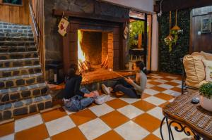 孔斯坦萨Hotel Rancho Constanza & Cabañas de la Montaña的两人坐在壁炉前的地板上