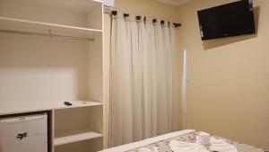 布罗塔斯Belo Quinto Styles的一间卧室配有一张床、一台电视和一个衣柜