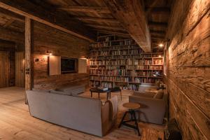 凯撒山麓舍福Luxury old wood mountain chalet in a sunny secluded location with gym, sauna & whirlpool的带沙发、椅子和书架的图书馆